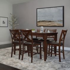 a dining room table and chairs in front of a painting on the wall above it