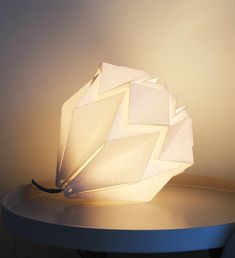 a white lamp sitting on top of a table next to a black corded phone