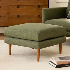 a green chair and footstool sitting in front of a dresser with books on it