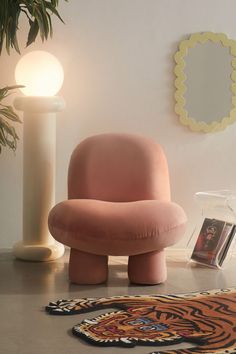 a pink chair sitting on top of a rug next to a lamp and mirror in a room