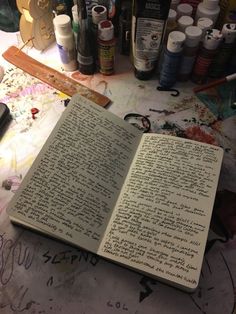 an open book sitting on top of a table covered in lots of crafting supplies