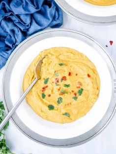 two white bowls filled with hummus and garnished with cilantro