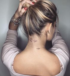 a woman with a bird tattoo on her neck and behind her head is looking at the camera