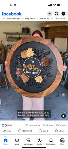 a woman is holding a wooden sign with leaves on it and the words facebook are in front of her