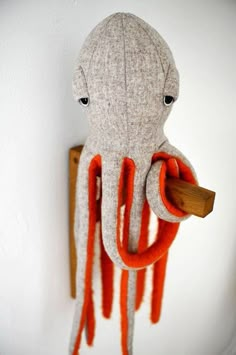 an octopus stuffed animal hanging on the wall with a piece of wood in it's mouth