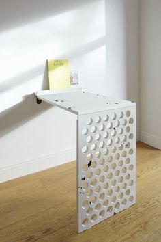 a white table sitting on top of a hard wood floor next to a book shelf