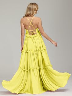 the back of a woman wearing a yellow long dress with straps and ruffles