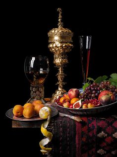 a table topped with a bowl of fruit next to a wine glass and goblet