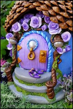 a purple fairy door in the grass with flowers