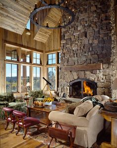 a living room filled with furniture and a fire place next to a stone wall covered in logs