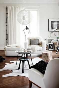 two pictures of a living room with white furniture and wood floors, one in black and white