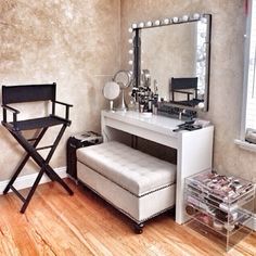 a dressing room with a vanity, stool and mirror on the wall next to a window