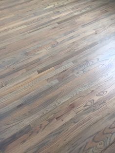 an empty room with hard wood flooring in the middle and sunlight coming through the window