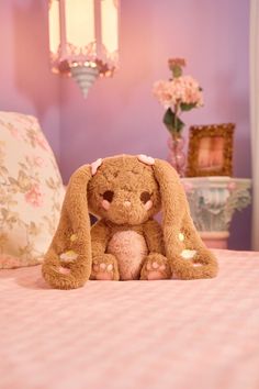 a brown stuffed animal sitting on top of a bed next to a pink comforter