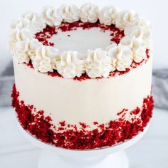 a red velvet cake with white frosting and sprinkles on a pedestal