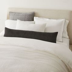 a bed with white linens and black pillows