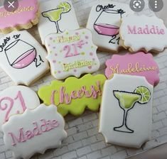 decorated cookies are arranged on a table with pink and green accents, including the words happy 21st birthday to all of them