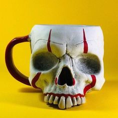 a coffee mug with a skull face on it's side and red stripes around the eyes