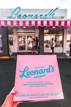 a person holding up a sign in front of a store that says lemonade's bakery