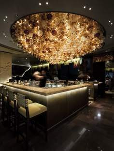 a large chandelier hanging from the ceiling above a bar with chairs and stools