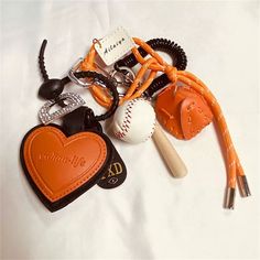 an orange heart shaped keychain with baseballs and other items attached to it