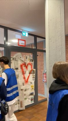 some people are walking in front of a building with graffiti on the wall and newspaper