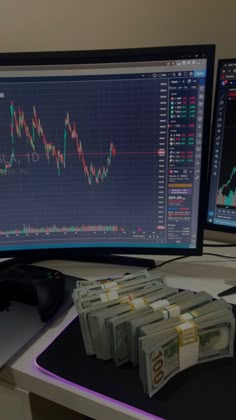 a computer monitor with stacks of money on the desk next to it and a mouse