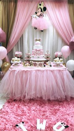 a minnie mouse themed birthday party with pink tulle skirt, cake table and balloons