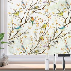 birds are sitting on the branches of a tree outside window sill with flowers in front of it