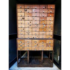 an old wooden cabinet with lots of drawers and knobs on the front, sitting in a storage area