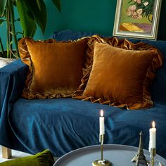 a blue couch with two pillows on top of it next to a table and candles