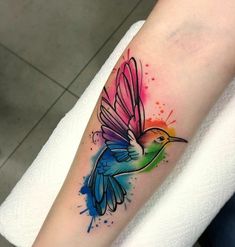 a colorful humming bird tattoo on the arm