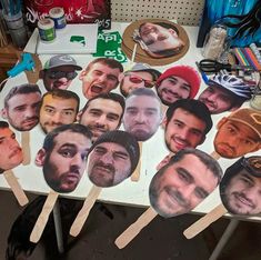 a table topped with lots of cut outs of men's faces on wooden skewers