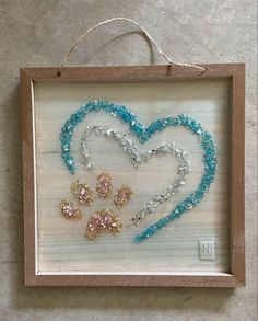 a wooden frame with beaded dog's paw and heart in the shape of a heart