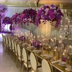 a long table is set with white chairs and purple flowers