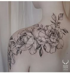 the back of a woman's shoulder with flowers on it and leaves around her