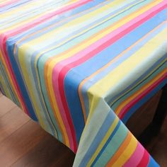 a table with a multicolored striped cloth on it's top and wooden floor