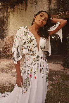 a woman wearing a white dress with flowers on it