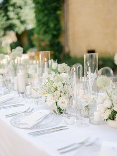 the table is set with white flowers and silverware for an elegant wedding reception or special event