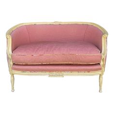 a pink couch sitting on top of a white floor next to a wooden frame with gold trim