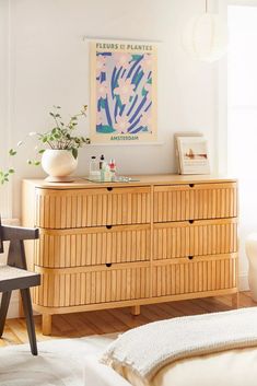 a room with a dresser, chair and painting on the wall