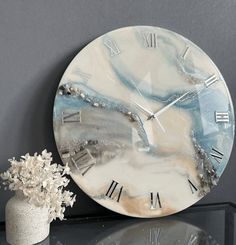 a clock sitting on top of a table next to a vase