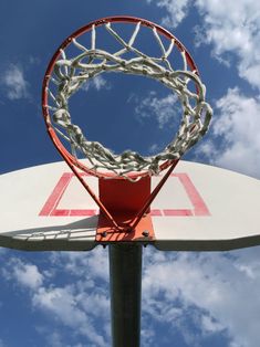 a basketball hoop with the net in front of a blue sky and white cloud filled sky