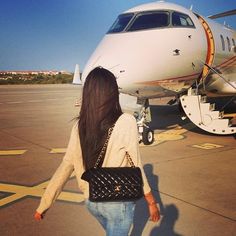 a woman walking towards an airplane on the tarmac with her hand in her pocket