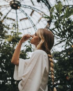 a woman with braids standing in front of a ferris wheel looking at the sky