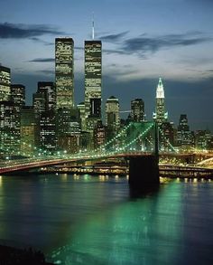 the city skyline is lit up at night, with skyscrapers and bridges in the foreground