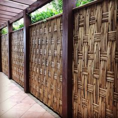 a wooden fence made out of bamboo sticks on the side of a building with tile flooring