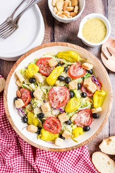 a white bowl filled with salad next to bread and dipping sauces on the side