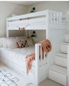 a white bunk bed sitting in a bedroom next to a stair case filled with drawers