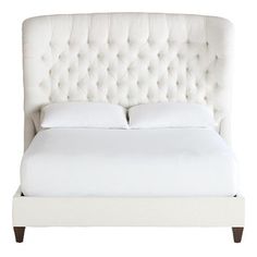 a bed with white linens and pillows on it's headboard, in front of a white background